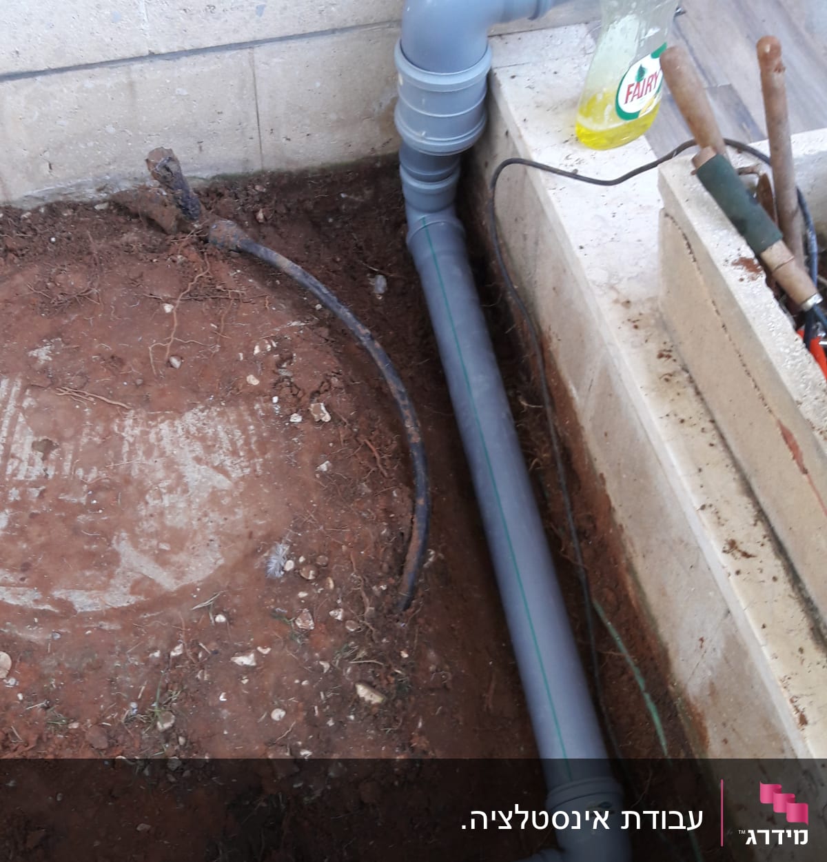 צינור פלסטיק אפור מותקן ליד קיר בטון